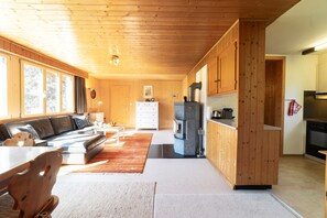 Una cocina moderna con armarios de madera, horno empotrado y una zona de comedor con sofá y mesa.
