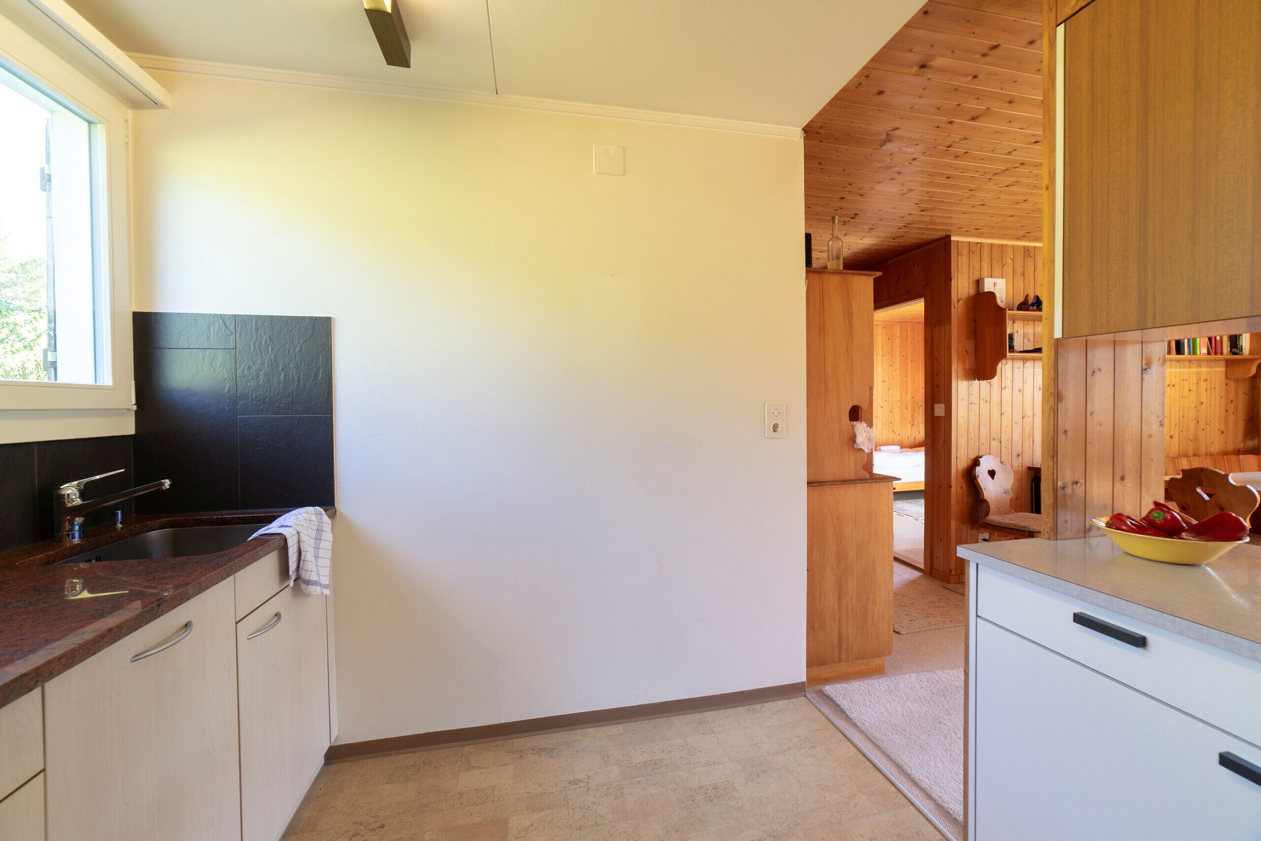 A kitchen with a granite countertop, white cabinets, and a wooden ceiling.