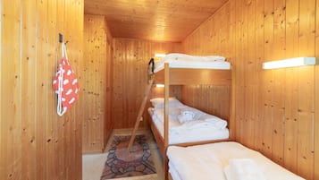 A wooden cabin with bunk beds, a patterned rug, and a hanging bag.
