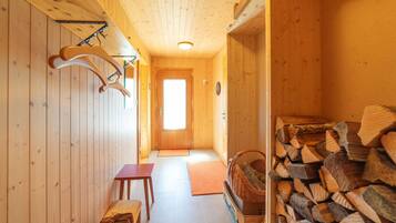 A wooden interior with a bench, a door, and a stack of firewood.