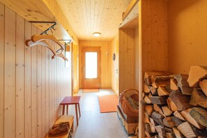 A wooden interior with a bench, a door, and a stack of firewood. - Dorea holiday home with mountain views (Wildhaus)