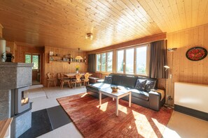 A cozy cabin interior with a dining area, a sofa, and a kitchen. - Dorea holiday home with mountain views (Wildhaus)