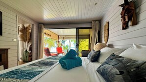 A spacious bedroom with a large bed, a view of the outdoors, and a unique wall art piece.