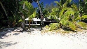 A beachside property with a white building, palm trees, and a clear blue sky.