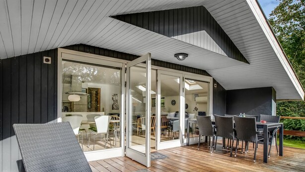 A modern outdoor deck with a glass door leading to a dining area, featuring a wooden deck and outdoor furniture. - "Dimo" - 30km from the sea by Interhome (Toftlund)
