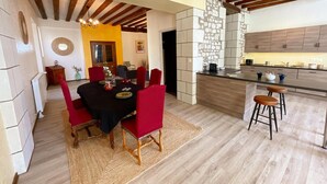 Uma área de refeições com toalha de mesa preta, cadeiras vermelhas e um tapete tecido.