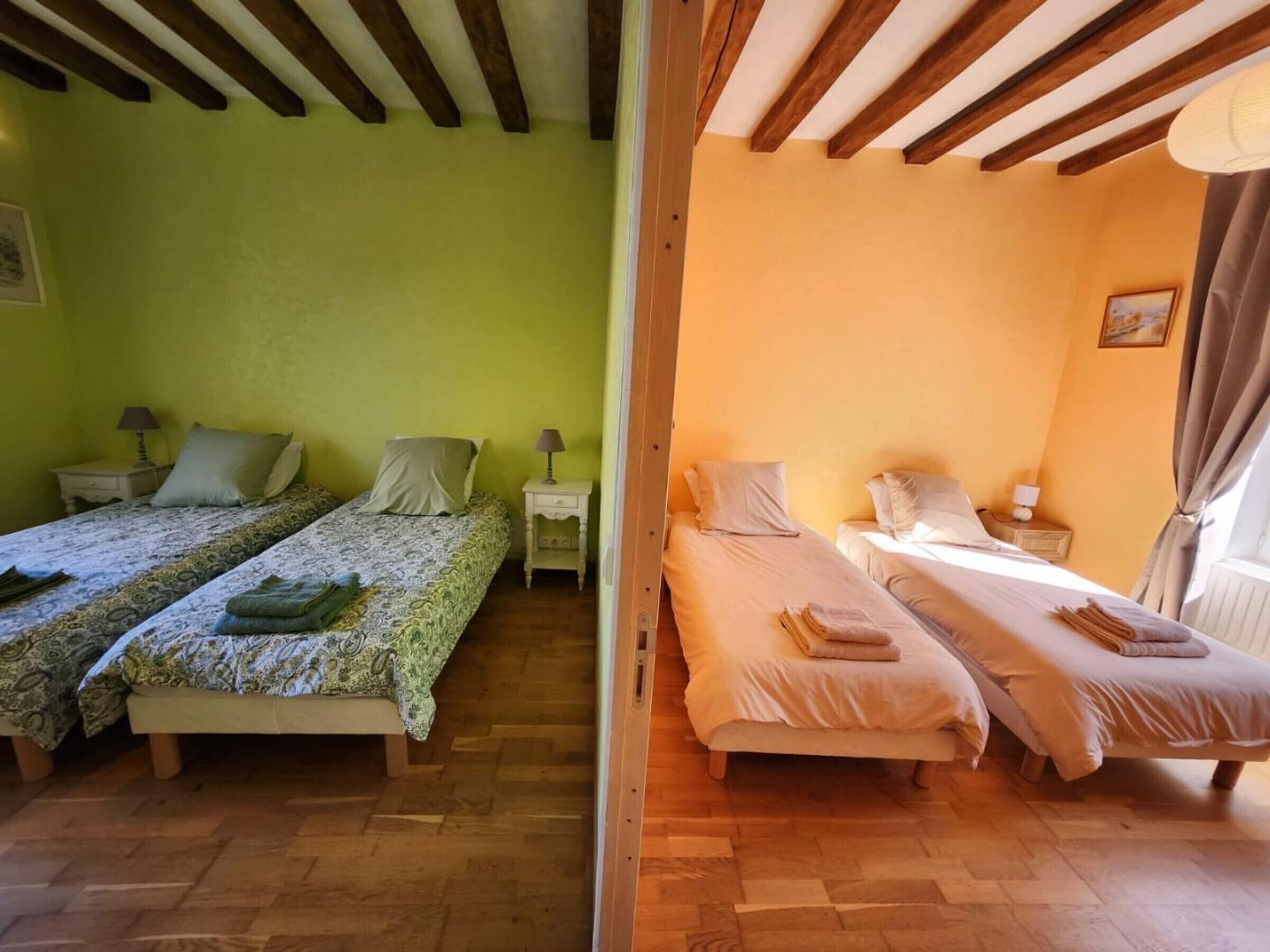Una habitación con dos camas, suelo de madera y techo con vigas a la vista.