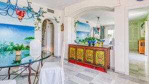 A dining area with a glass table, chairs, and a decorative cabinet with floral patterns.
