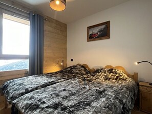 A bedroom with a wooden headboard, a bed with a patterned bedspread, a nightstand with a lamp, and a framed picture on the wall.