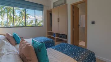 Habitación de hotel con dos camas, un armario y vistas a palmeras.