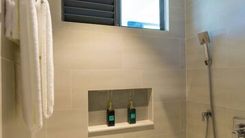 Un baño moderno con ducha, una ventana y dos botellas de champú en una estantería.