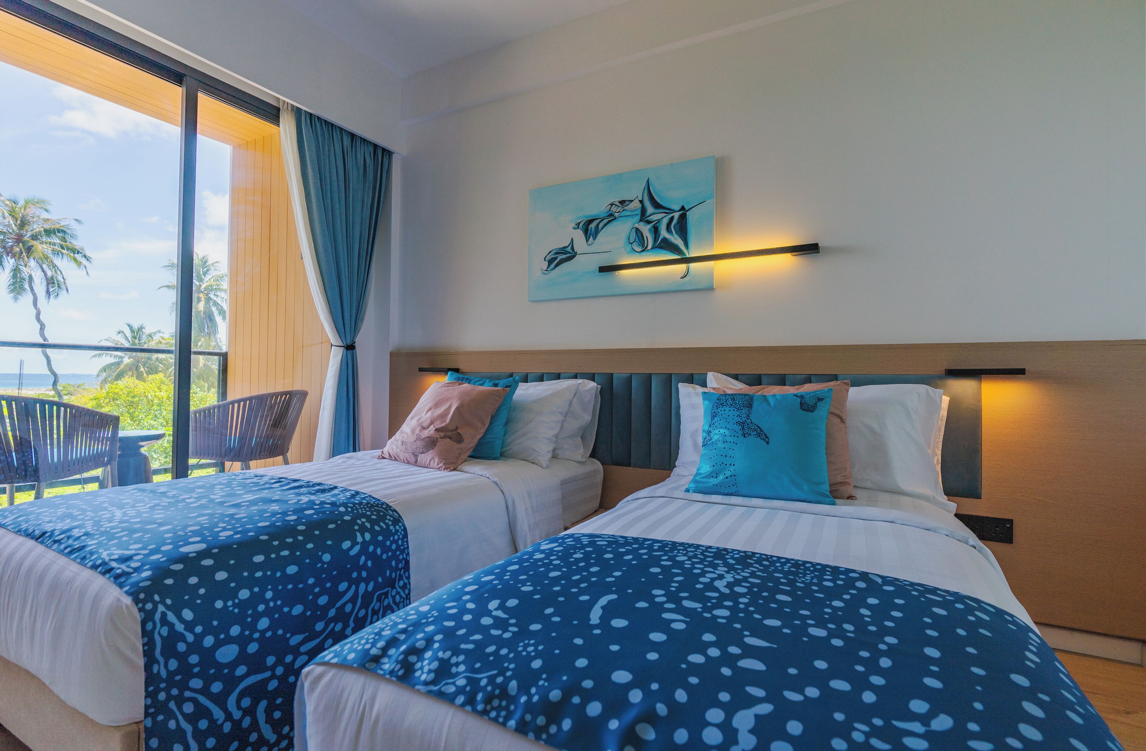 A hotel room with two beds, a large window with a view of palm trees, and a painting on the wall.