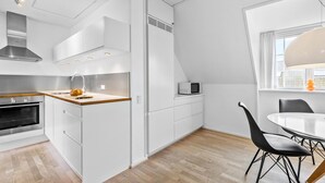 A modern kitchen with white cabinetry, a wooden countertop, and a built-in oven.