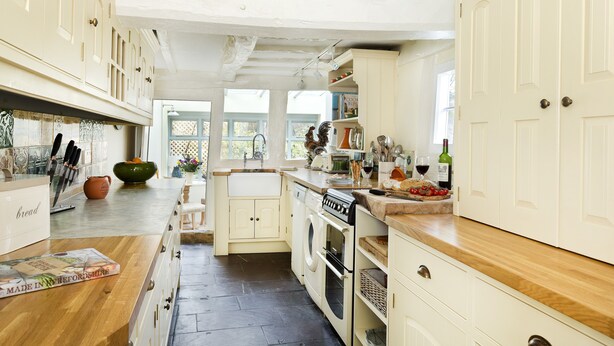A spacious kitchen with white cabinetry, a wooden countertop, and a view into the dining area.