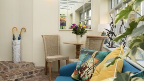 A cozy seating area with a blue sofa, wicker chairs, and a small table with a vase of flowers.