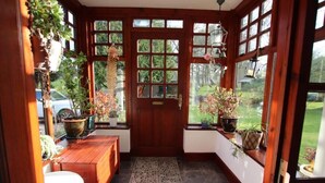 A wooden door with a grid pattern, flanked by windows with plants.