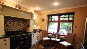 A kitchen with a tiled backsplash, a stove, and two wicker chairs.