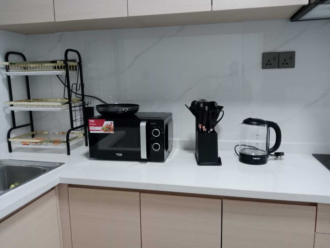 Et køkken med mikrobølgeovn, kaffemaskine og bestik på bordet.