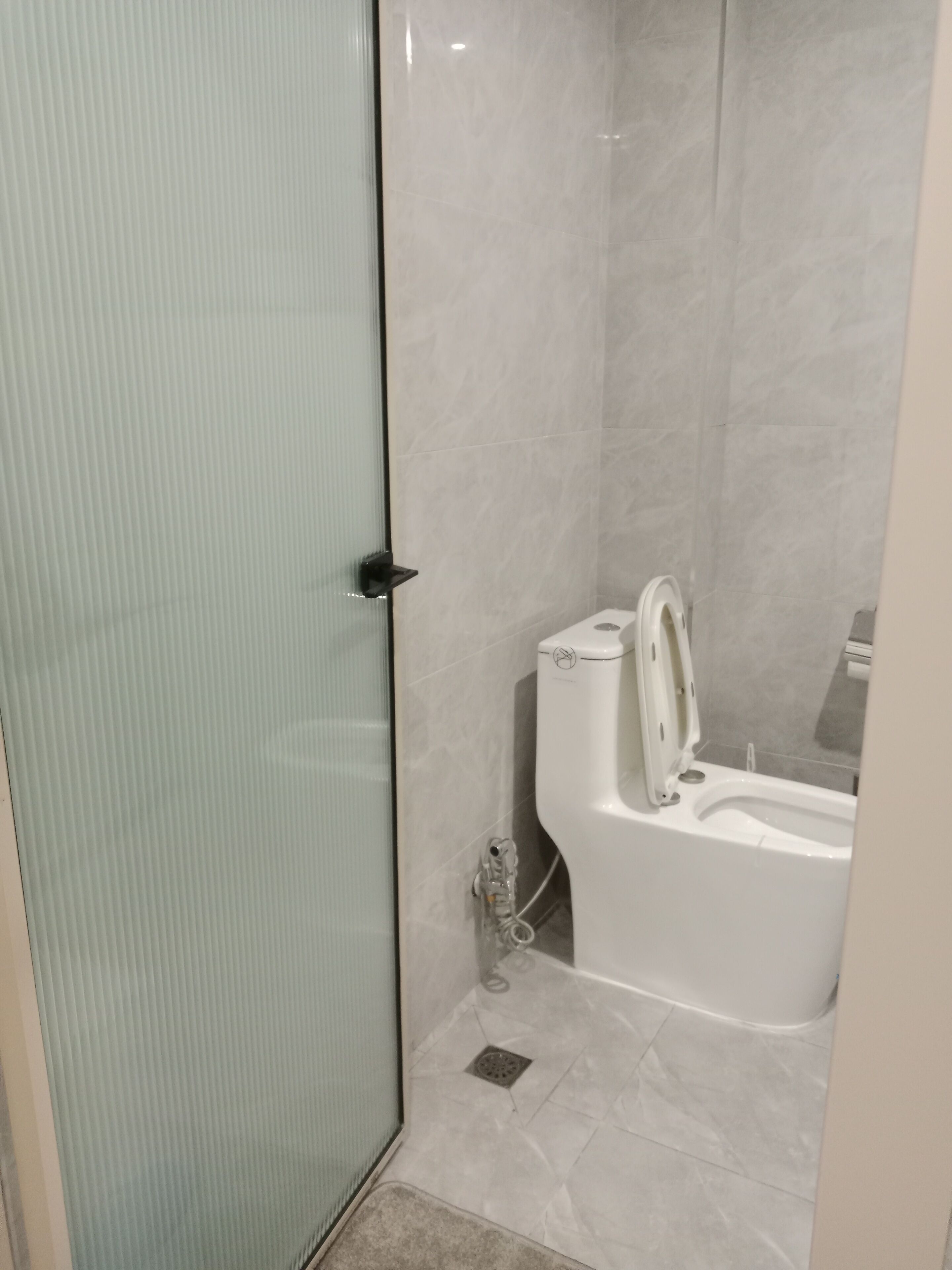 Een badkamer met een douchecabine van glas, een wit toilet en een bad.