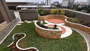 A rooftop garden with a circular design, featuring a central planter and surrounding grass areas. - Benedictions Homes (Nairobi)