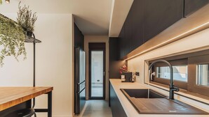 A modern kitchen with a wooden countertop, black faucet, and a potted plant. - Nos Aqua Villas (Chania)