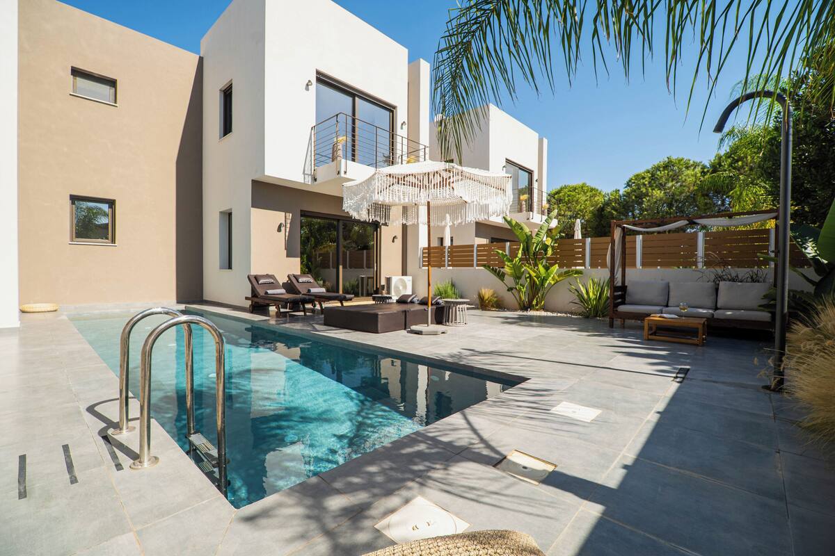 A modern outdoor pool area with a built-in pool, lounge chairs, and a wooden deck.