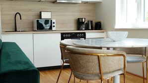 A modern kitchen with a microwave, coffee maker, and oven. There is a round dining table with chairs. - 1 Zimmer Apartment mit Blick auf die Stadt (Gmunden)