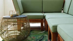 A corner seating area with a woven chair, cushioned benches, and a small table with candles. - 1 Zimmer Apartment mit Blick auf die Stadt (Gmunden)