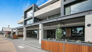 Un bâtiment moderne doté d’un toit plat, de grandes fenêtres et d’un jardinier en bois placé à l’avant.