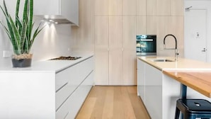 Une cuisine moderne avec des armoires blanches, un plan de travail en bois et un four encastré.