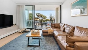 Un salon moderne avec un canapé en cuir, un téléviseur à écran plat et une table basse.