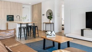 Un salon moderne avec un canapé, une table basse et un téléviseur. Il y a également un coin cuisine avec une table à manger et des chaises.