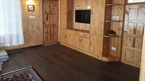 A wooden-paneled room with a television, cabinets, and a rug. - Heaven Inn Manali (Manali)