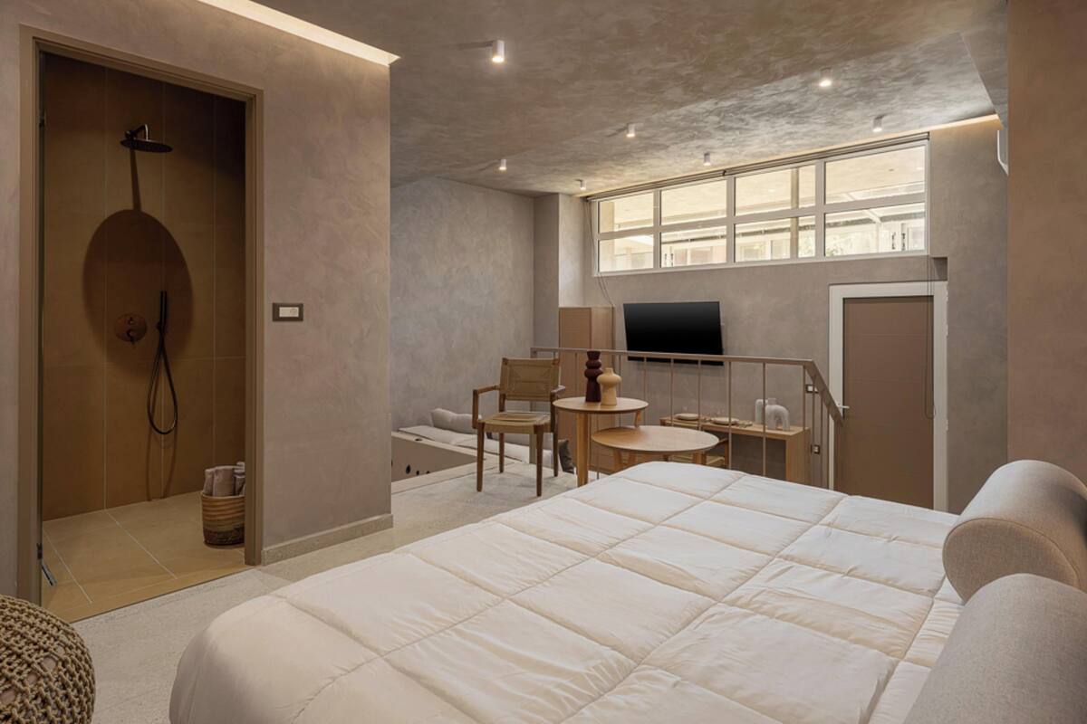 Une chambre d’hôtel moderne dotée d’un grand lit, d’une douche, d’un petit coin salon et d’une télévision.