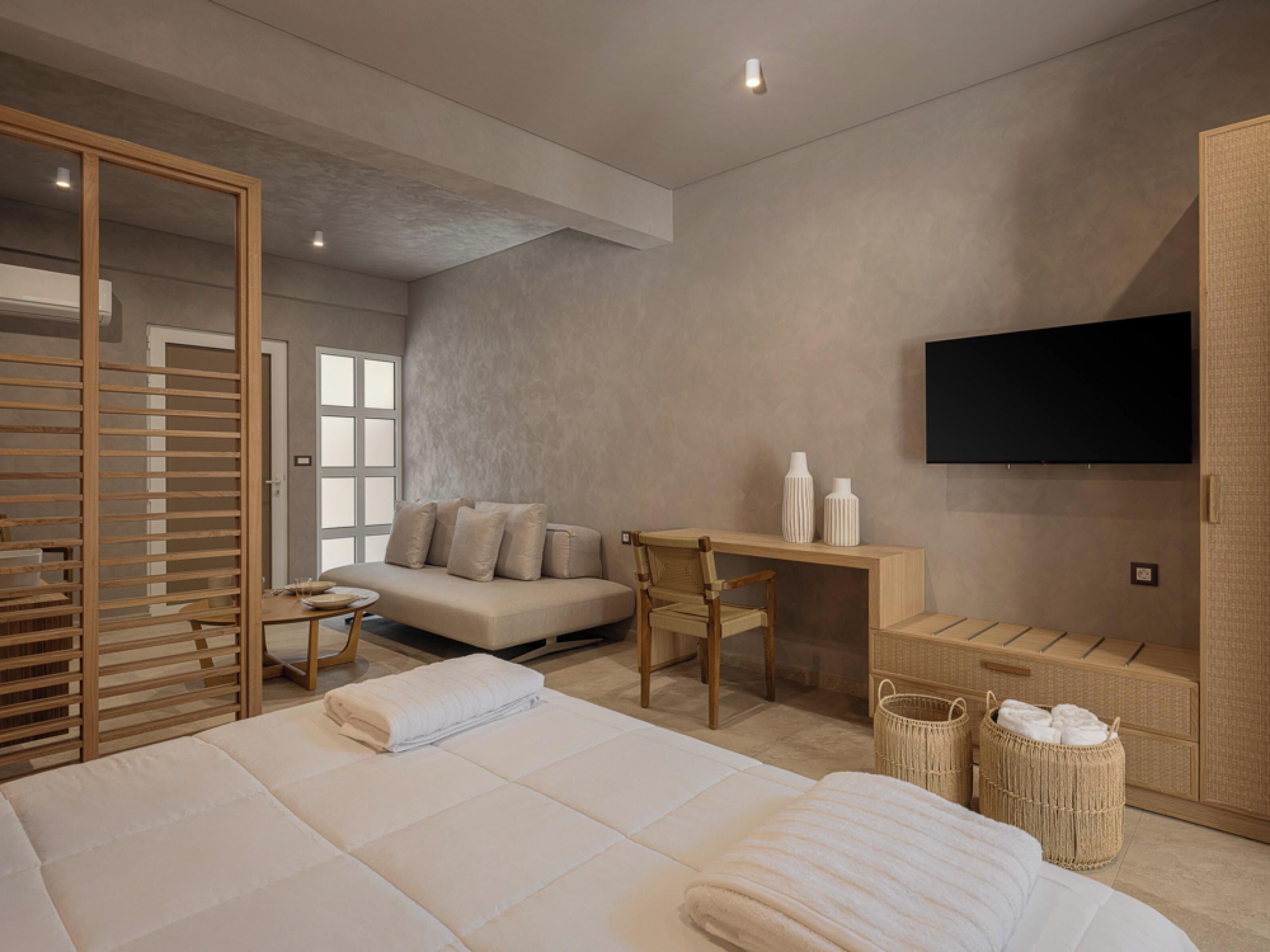 Une chambre à coucher moderne avec un grand lit, un canapé, un bureau et un téléviseur fixé au mur.