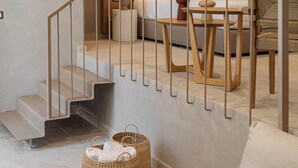 Ein modernes Interieur mit Treppe, einer Couch, einem Tisch und Korbwannen.