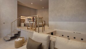 Ein modernes, minimalistisches Schlafzimmer mit einem großen Bett, einer Couch und einer Treppe, die in einen oberen Bereich führt.