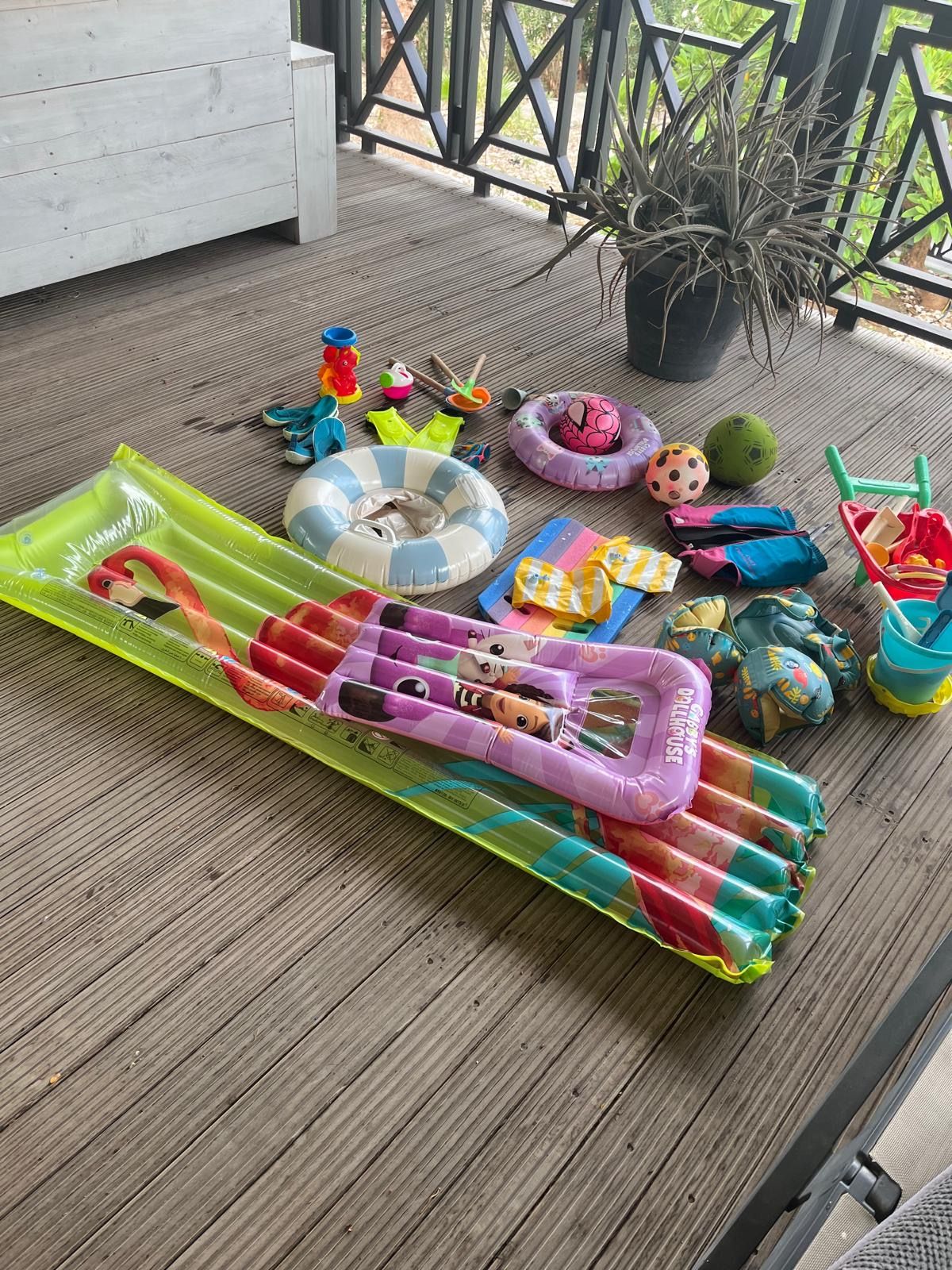 A wooden deck with a colorful inflatable pool, children's toys, and a potted plant.