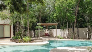 A swimming pool with a wooden deck and a covered seating area surrounded by trees. - Catch Soulful Vibes at AHAL II! Enjoy a private plunge pool and a communal pool! (Tulum)