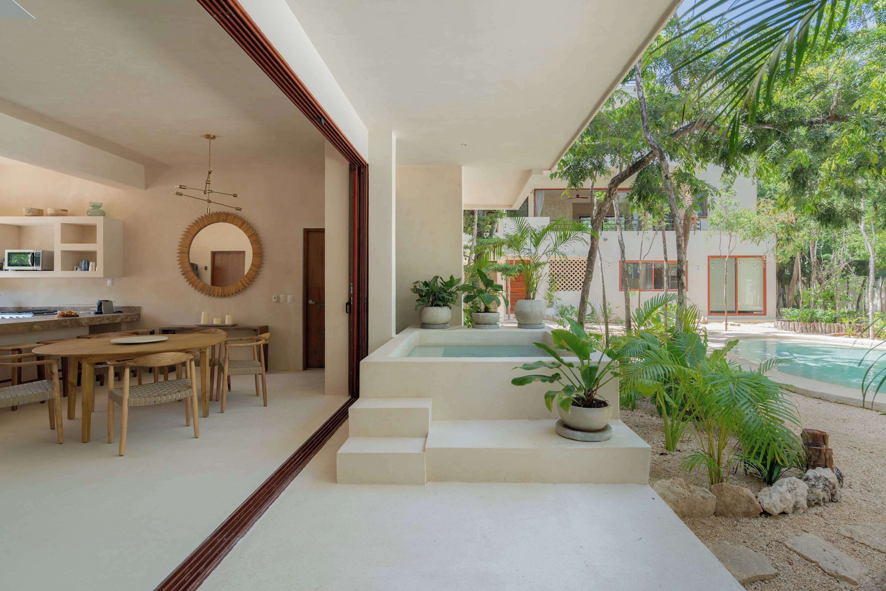 A modern interior with a dining area, a kitchen, and a poolside area with steps leading to the pool.