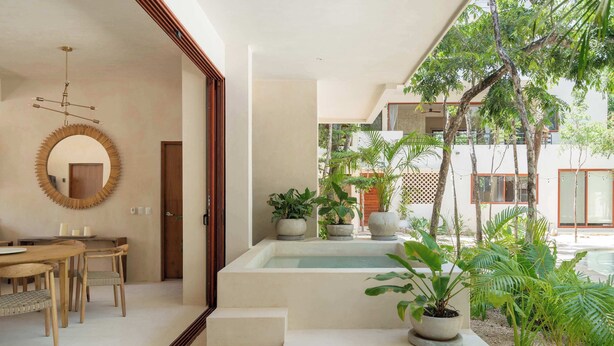 A modern interior with a dining area, a staircase leading to an outdoor space, and a water feature. - Catch Soulful Vibes at AHAL II! Enjoy a private plunge pool and a communal pool! (Tulum)