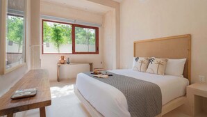 A bedroom with a large bed, a wooden nightstand, a bedside table with a remote control, a window with a view of trees, and an air conditioning unit on the wall. - Catch Soulful Vibes at AHAL II! Enjoy a private plunge pool and a communal pool! (Tulum)