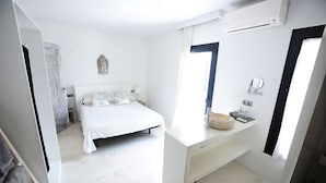 A bedroom with a bed, a bedside table, a mirror, and an air conditioning unit. - My Rental Homes - Villa Seahorse private pool and air conditioning (Cala Llonga)