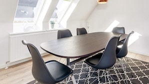 A modern dining area with a round table, black chairs, and two copper pendant lights. - 4 Person Holiday Home in Frederikshavn (Frederikshavn)
