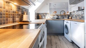 A modern kitchen with a wooden countertop, built-in appliances, and a tiled backsplash. - 4 Person Holiday Home in Frederikshavn (Frederikshavn)