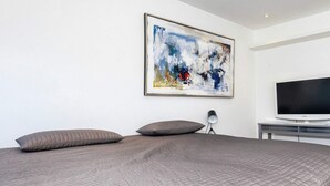 A modern bedroom with a large bed, a flat-screen TV, and a framed abstract painting on the wall. - 4 Person Holiday Home in Frederikshavn (Frederikshavn)