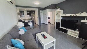 Ein modernes Wohnzimmer mit grauem Sofa, weißem Couchtisch und Flachbildfernseher.