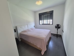 Un dormitorio con cama, ventilador y ventana.