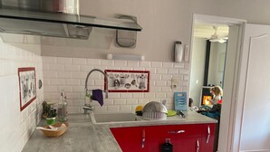 A kitchen with white subway tiles, a red island, a stainless steel range hood, and a small sink. - 3-bedroom house for 6 people (Argelès-sur-Mer)