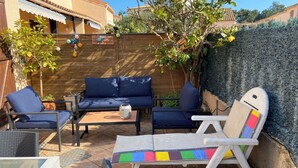 A patio with a blue sofa, a white lounge chair, and a small table. - 3-bedroom house for 6 people (Argelès-sur-Mer)